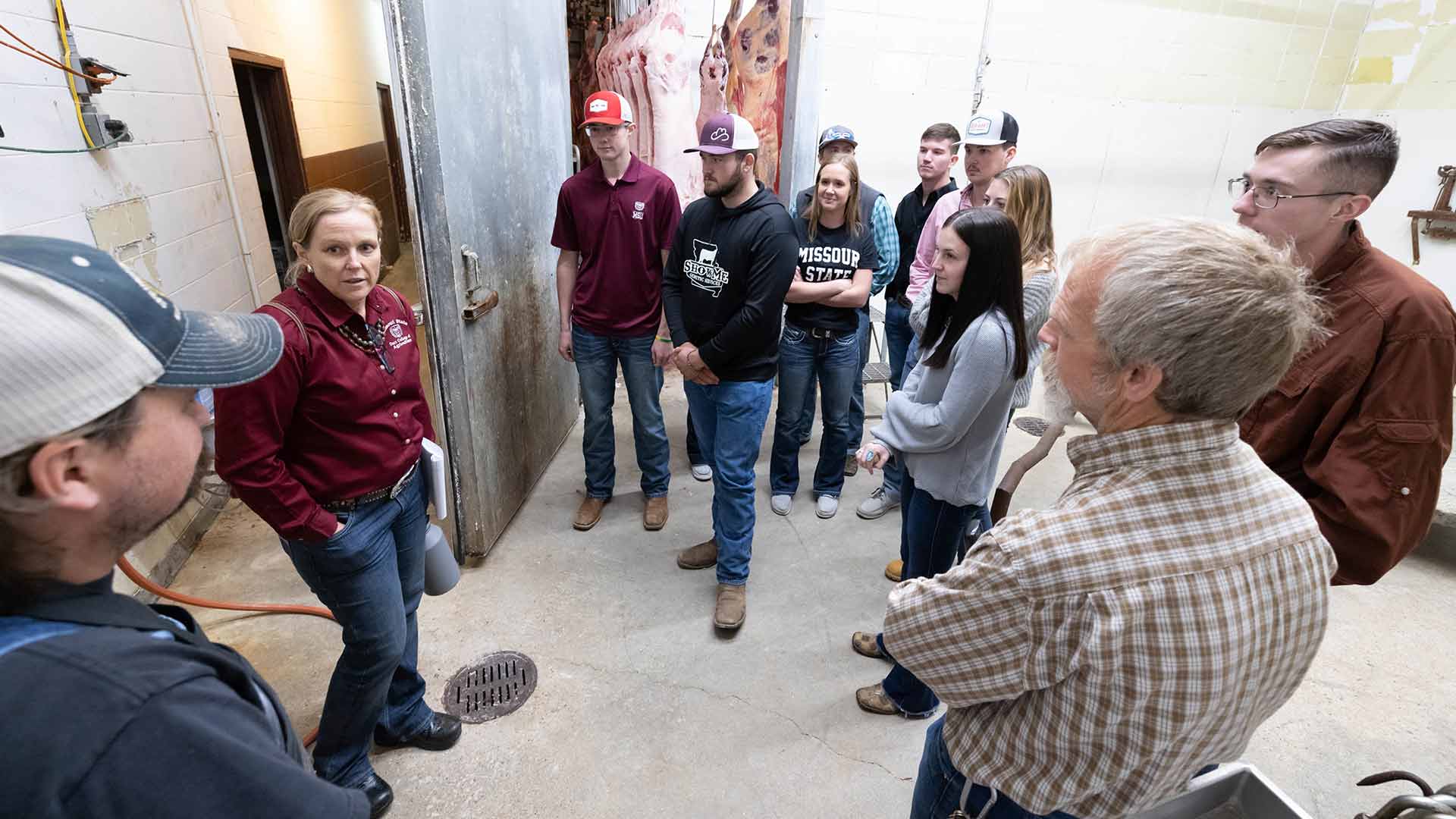 Students talking to owners of a meat processing plant during a class field trip.