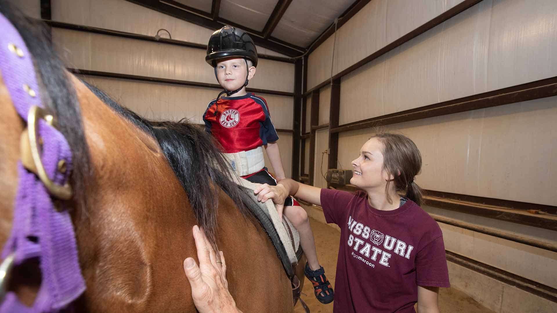 Equine student doing equine therapy session with child.