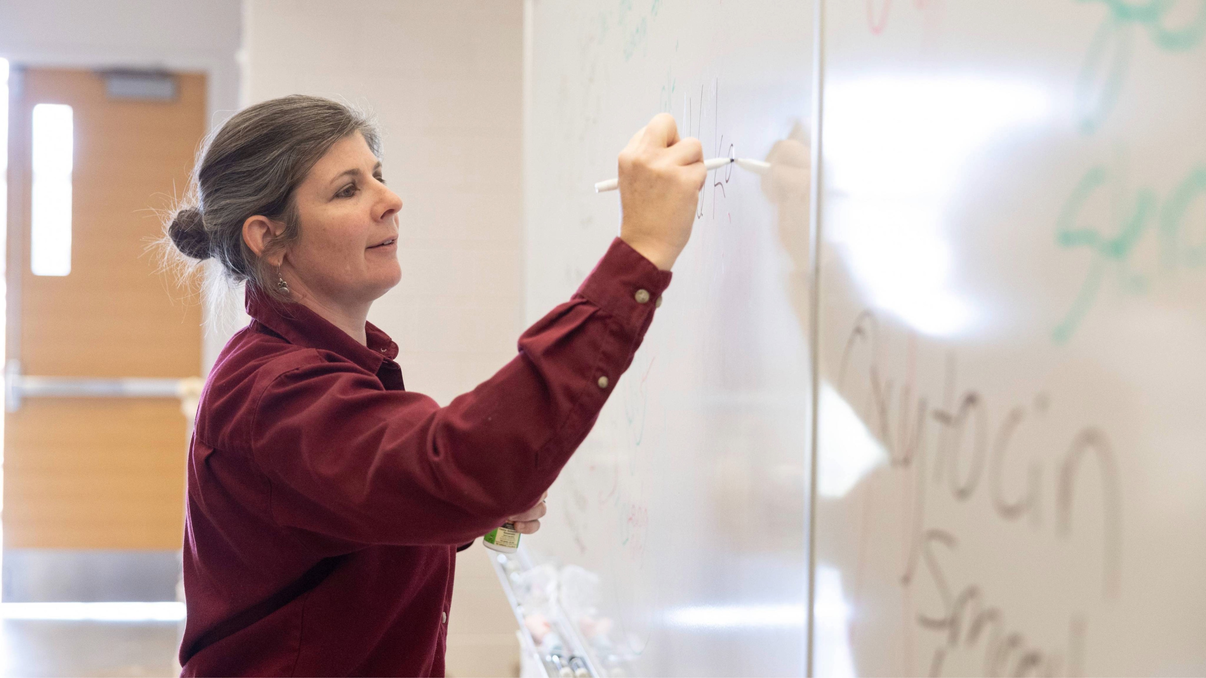 Dr. Lacy Sukovaty writing on a whiteboard in classroom