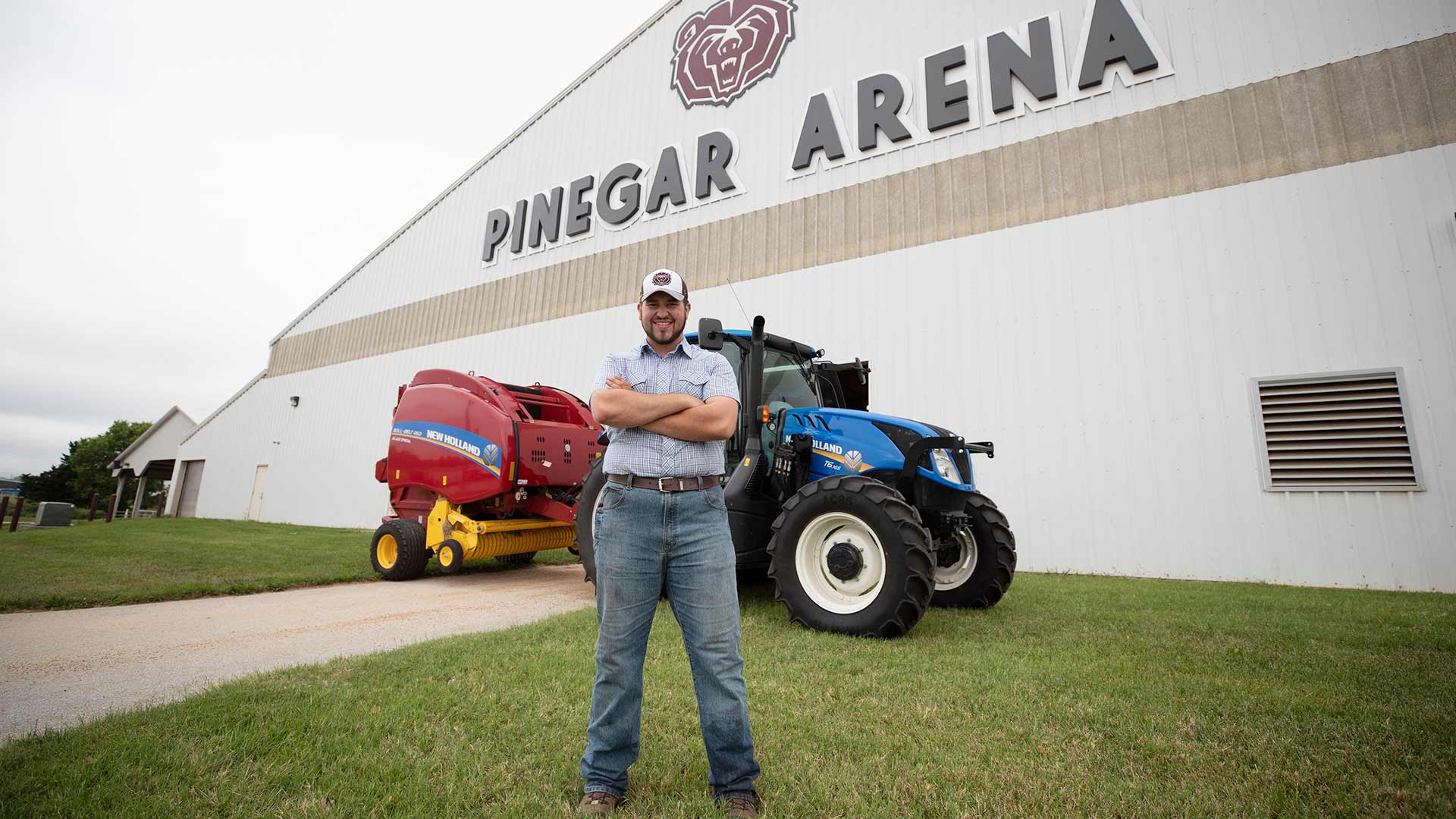 An agriculture student stands in front of a nice tractor at Pinegar Arena.