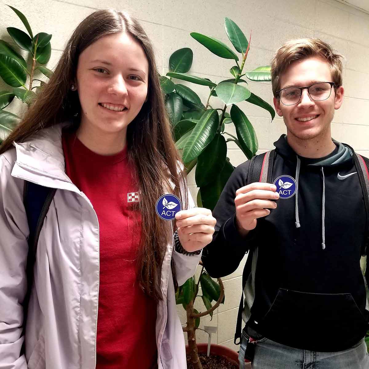 Two students holding up membership stickers they received from the National Agricultural Communicators of Tomorrow (ACT).