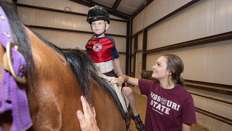 Equine student doing equine therapy session with child.