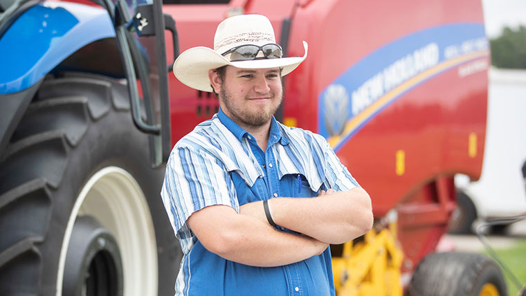 Student standing in front of tractor.