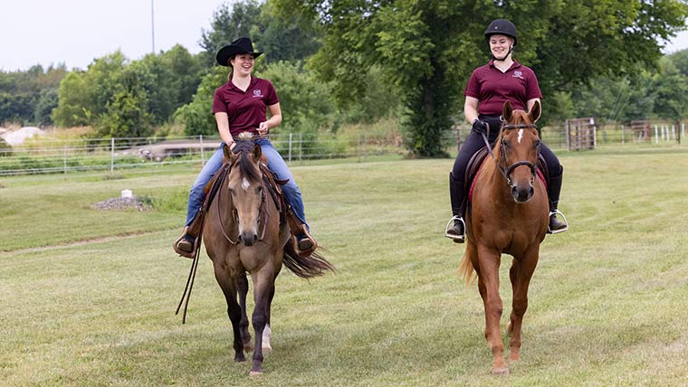 Two equine students riding their horses at Darr Agricultural Center.