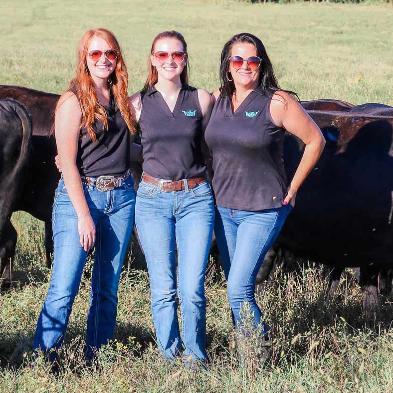 Macey Hurst with her sister and mom on their farm. Some cattle are pictured in the background.