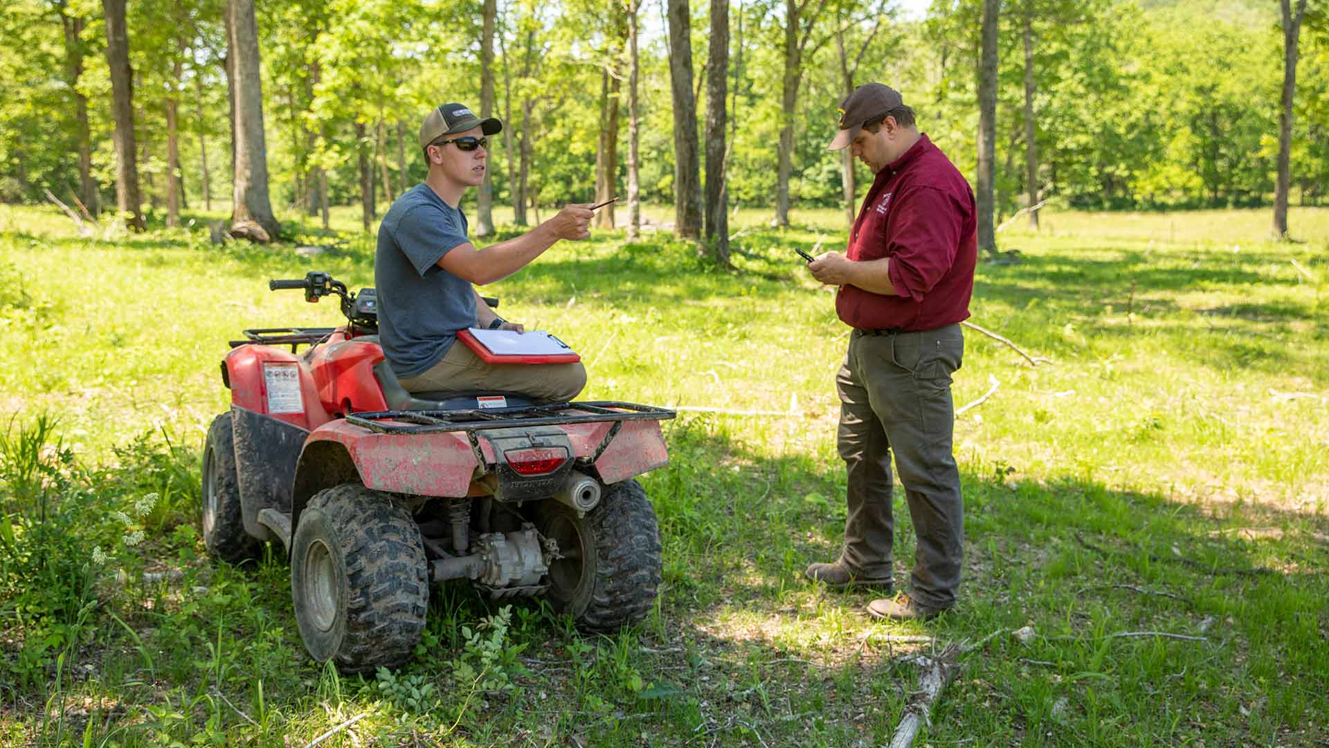 Dr. Michael Goerndt talks with a graduate student who's seated on an ATV during a research trip to Journagan Ranch.