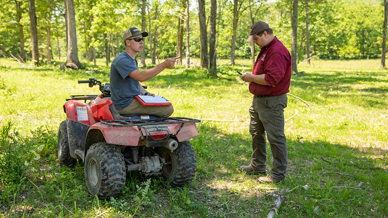 Dr. Michael Goerndt talks with a graduate student who's seated on an ATV during a research trip to Journagan Ranch.