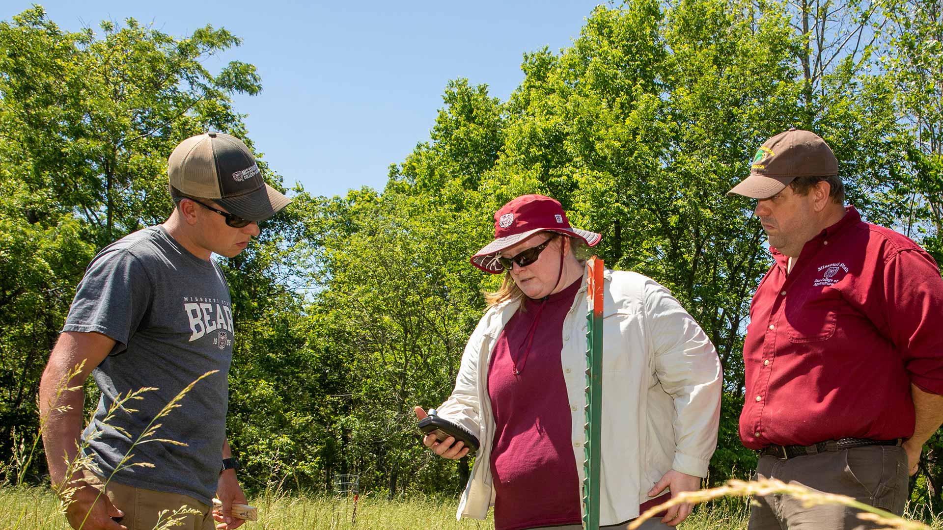 Dr. Melissa Bledsoe, Dr. Michael Goerndt and ag student Stewart McCollum inspect young walnut trees at a ranch in the Ozarks.