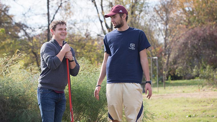 Two students taking a break while working in the community garden on campus.